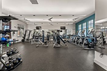 A gym with a variety of equipment including weights and cardio machines. at Bridge at Indigo, Austin, TX
